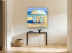 Two Chairs Beneath Umbrella coastal canvas print on the wall of a hallway
