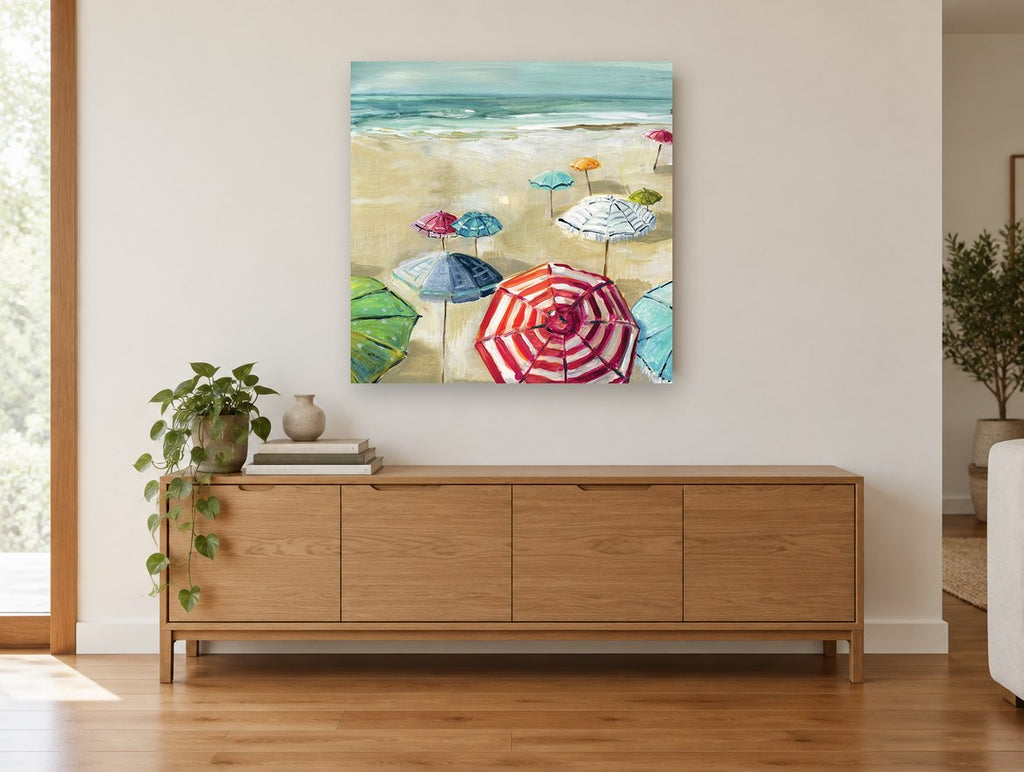 Striped Umbrellas on Sand coastal canvas print on the wall of a living room above a sideboard