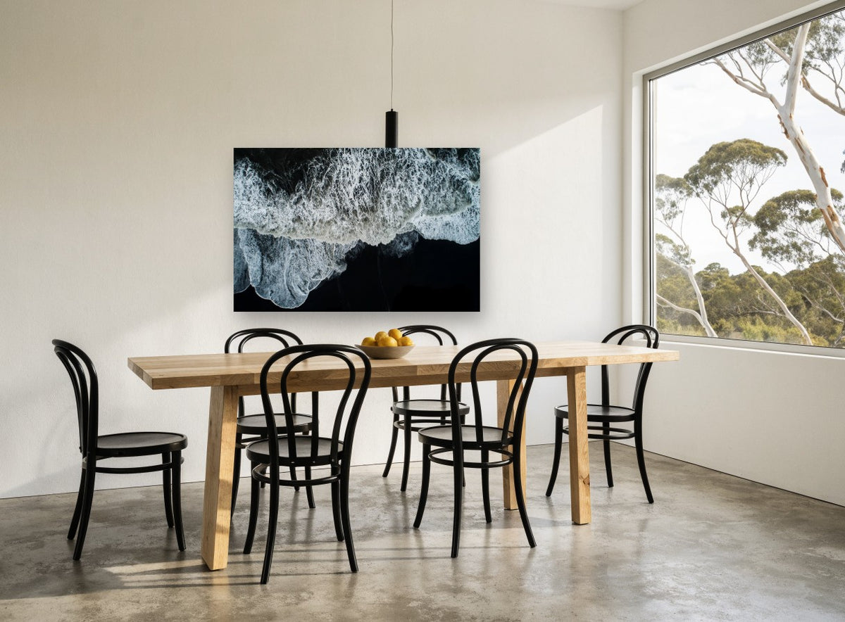 Foam on Black Sand coastal canvas print on the wall of a dining room