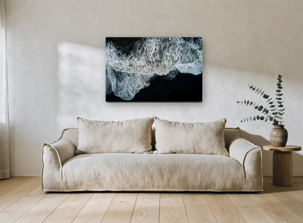 Foam on Black Sand coastal canvas print on the wall of a living room