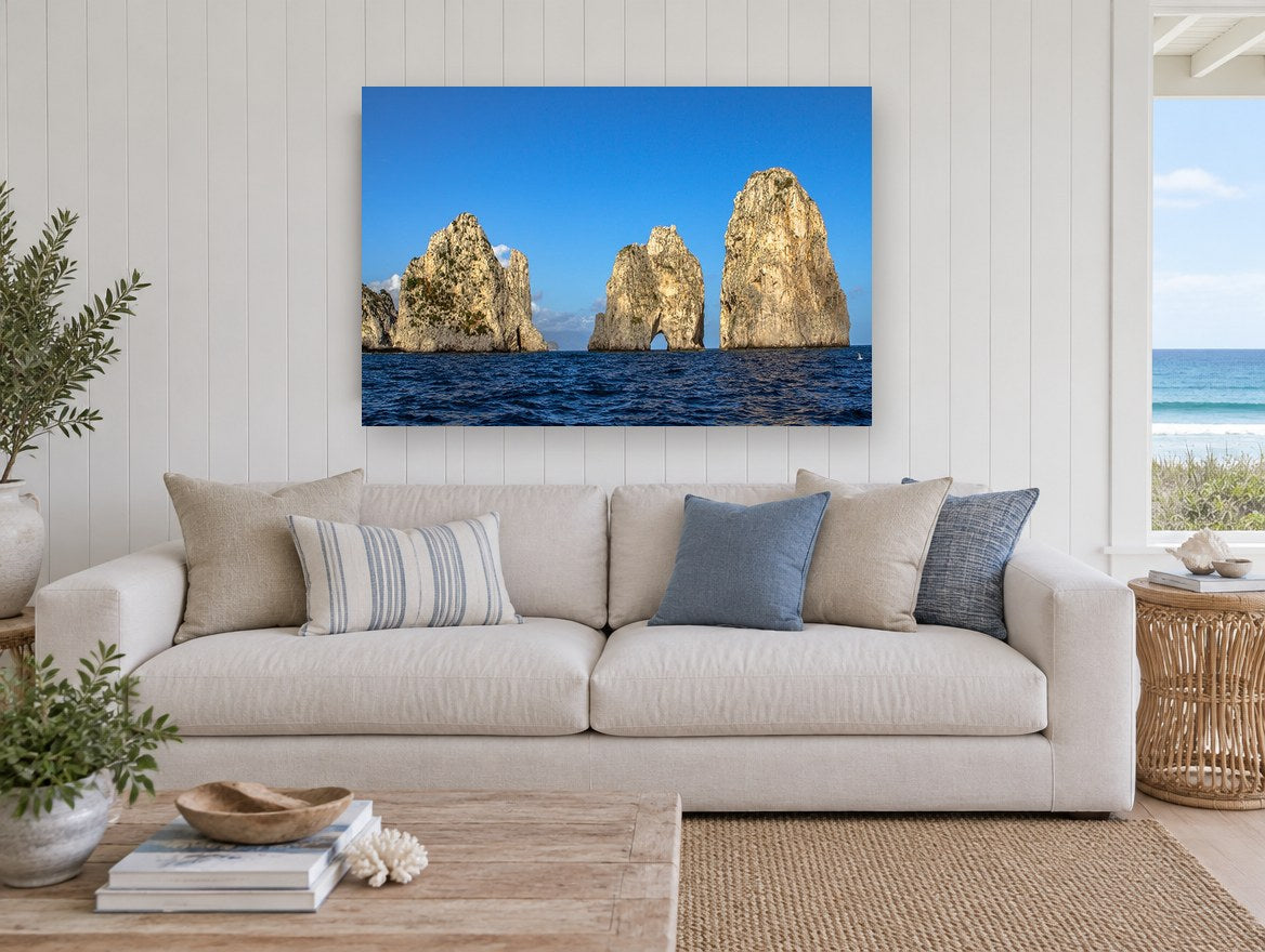 Three Sunlit Sea Stacks coastal canvas print on the wall of a beach house living room