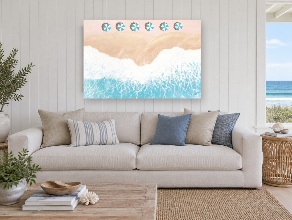 Pink Sand Umbrella Row coastal canvas print on the wall of a beach house living room
