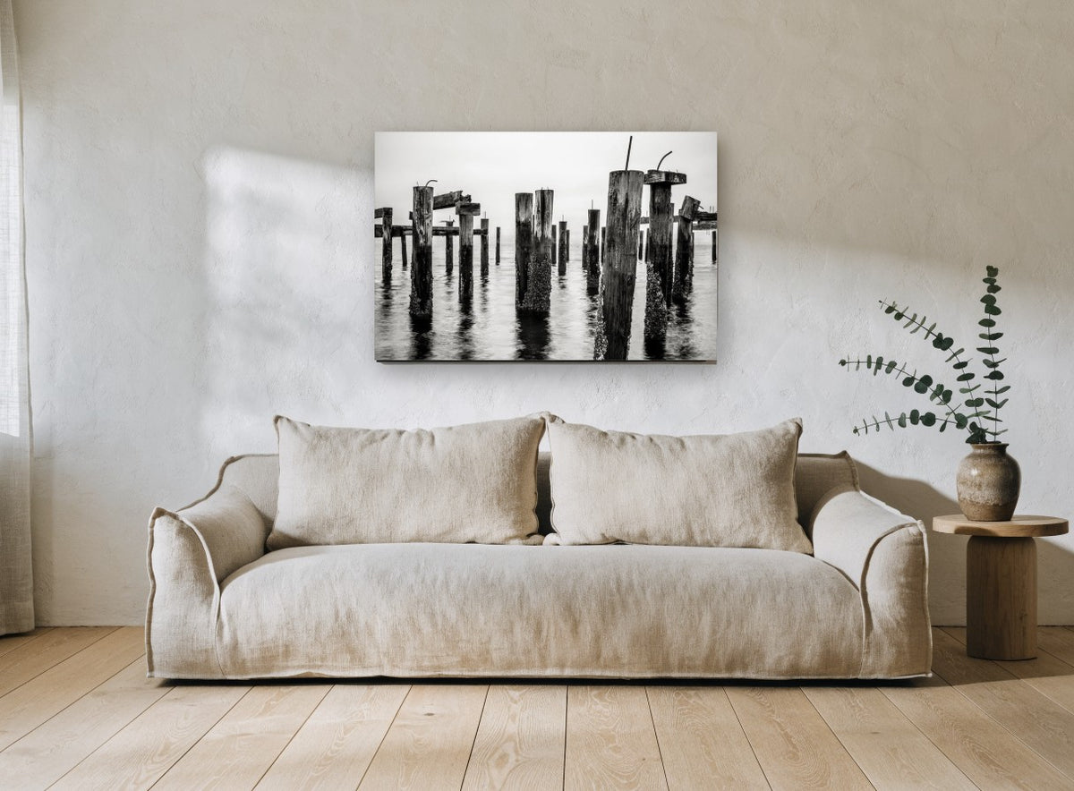 Barnacled Pier Posts coastal canvas print on the wall of a living room