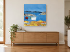 Three Boats Moored Cove coastal canvas print on the wall of a living room above a sideboard