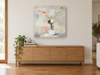 Lone Poppy in White Vase floral canvas print on the wall of a living room above a sideboard