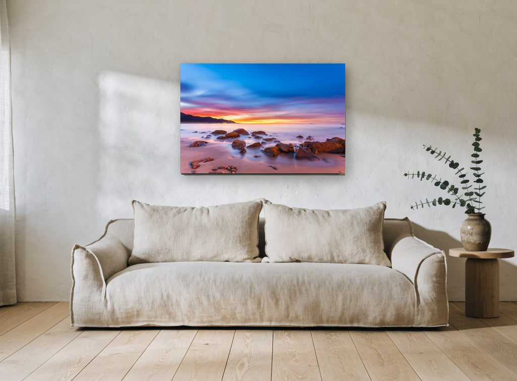 Dawn Glow Over Rocks coastal canvas print on the wall of a living room