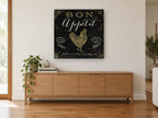 Bon Appétit Gold Rooster vintage canvas print on the wall of a living room above a sideboard