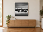 Still Water Rocks coastal canvas print on the wall of a living room above a sideboard