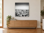 Pebble Shore Stillness coastal canvas print on the wall of a living room above a sideboard