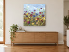 Meadow Under Blue Sky floral canvas print on the wall of a living room above a sideboard