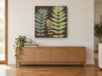 Three Fronds on Chocolate floral canvas print on the wall of a living room above a sideboard