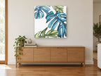 Teal Monstera Drift floral canvas print on the wall of a living room above a sideboard