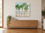 Palms Along the Shoreline coastal canvas print on the wall of a living room above a sideboard
