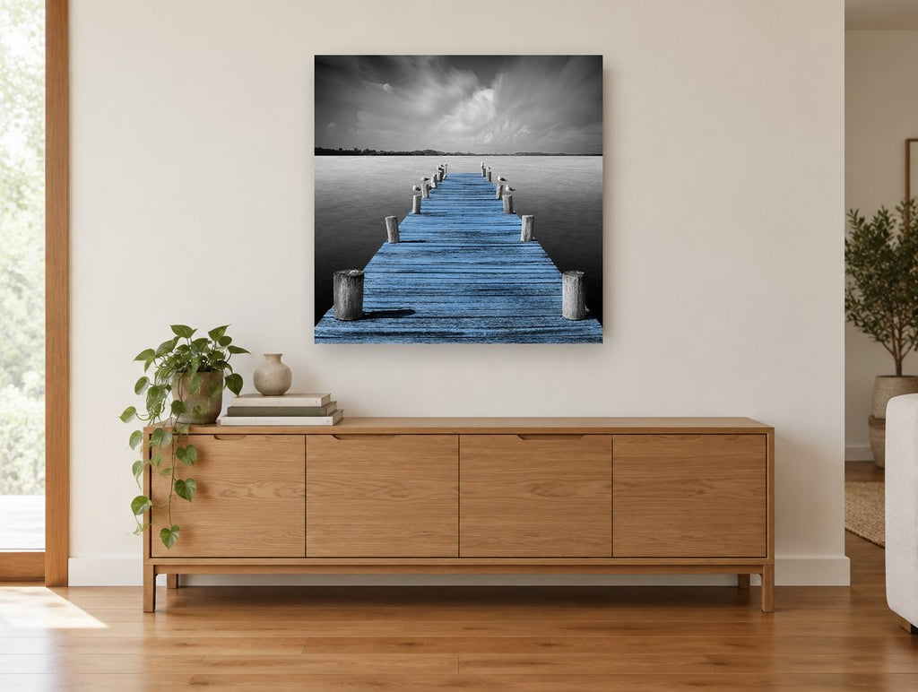 Blue Jetty Stillness coastal canvas print on the wall of a living room above a sideboard
