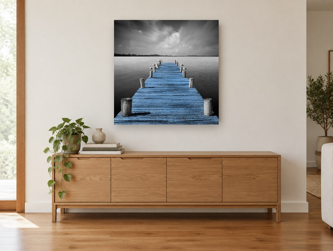 Blue Jetty Stillness coastal canvas print on the wall of a living room above a sideboard