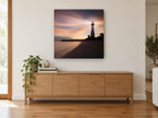 Lighthouse Dusk Glow coastal canvas print on the wall of a living room above a sideboard