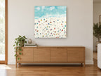 Sunbathers on Pale Sand coastal canvas print on the wall of a living room above a sideboard