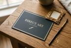 Direct Art Australia gift card with gold foil lettering beside an ornate gold frame